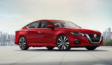 2023 Nissan Altima in red with city in background illustrating last year's 2022 model in Bedford Nissan in Bedford OH