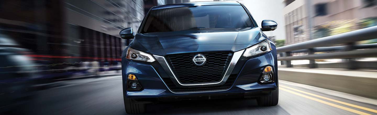 Image of a blue 2019 Nissan Altima driving on a city street.