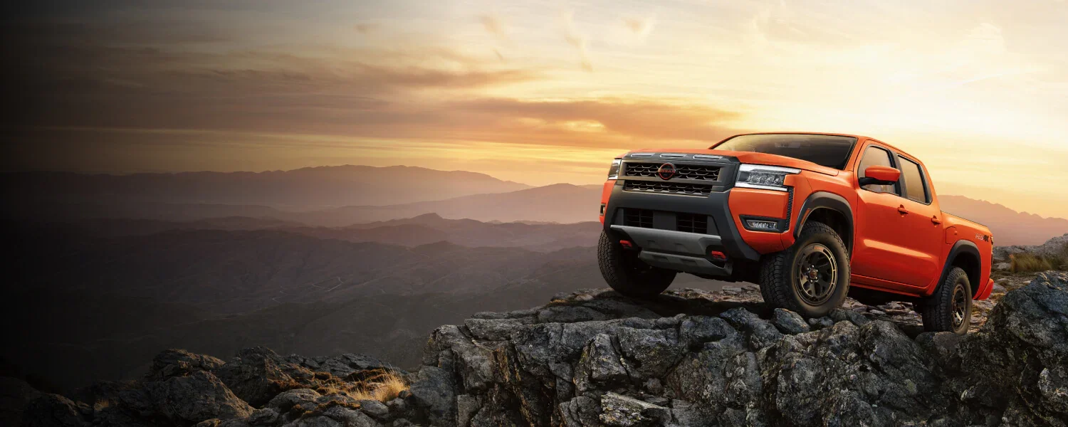 orange 2025 nissan frontier on top of rock
